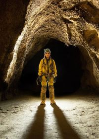 Full length of miner standing in cave