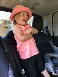 Cheerful girl standing in car