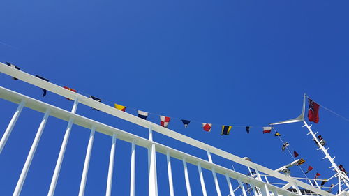 Low angle view of flags against clear blue sky