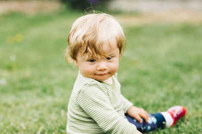 Close-up of cute boy sitting on field