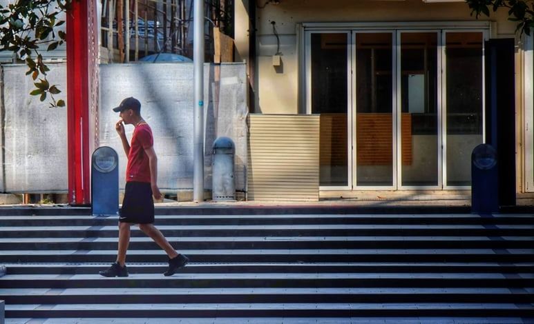 MAN WALKING IN FRONT OF BUILDING