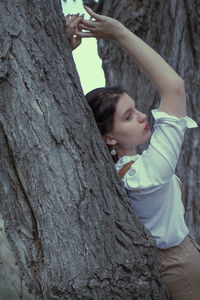 Low angle view of woman looking at tree trunk