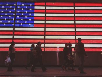 People walking in front of american flag in times square