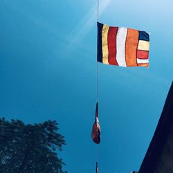 Low angle view of flags hanging against blue sky