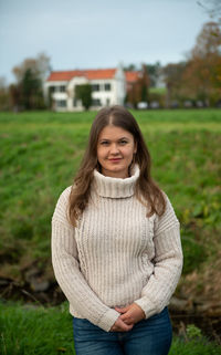 Portrait of a smiling young woman standing on field