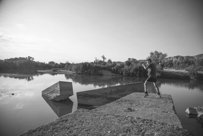 Woman standing by lake against sky