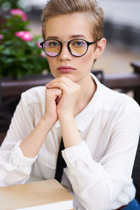 Portrait of young woman with eyeglasses on table