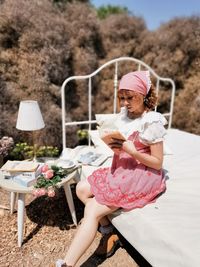 Full length of woman holding pink while sitting outdoors