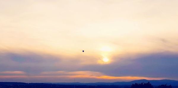 Silhouette of hot air balloons against sky during sunset