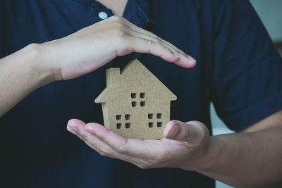 Close-up of man holding hand against house in building