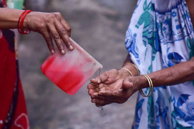 Cropped image of hand pouring water on woman hand