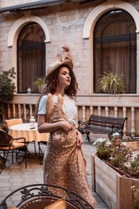 Portrait of smiling young woman standing against building