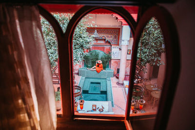 High angle view of woman seen through window sitting by swimming pool