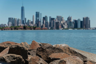 Sea by city buildings against clear sky