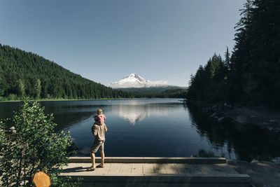 A father carries his daughter on his shoulders at trillium lake, or.