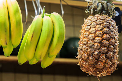 Pineapple and bunch of bananas hanged for sale