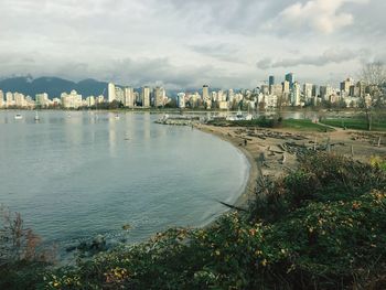 Scenic view of city by river against sky