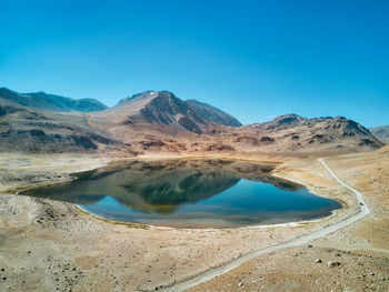 Scenic view of lake and mountains against clear blue sky