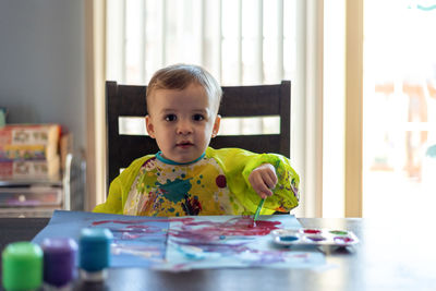 Portrait of cute girl painting on table at home