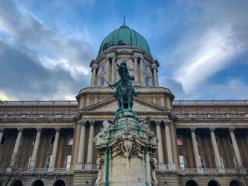 Low angle view of statue outside hungarian national gallery against cloudy sky