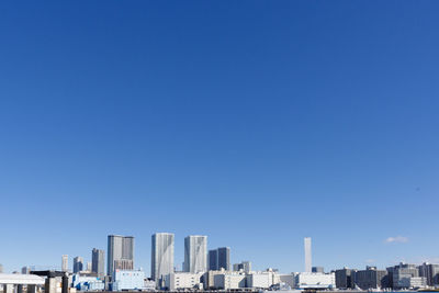 Modern buildings in city against clear blue sky