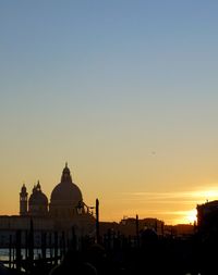 Silhouette buildings against clear sky during sunset