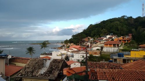 Houses by sea against sky in city