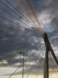 Low angle view of suspension bridge against cloudy sky