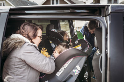 Parents adjusting girls on car seats