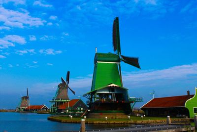 Traditional windmill by building against blue sky