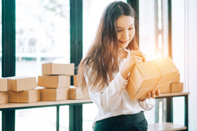 Beautiful young woman holding camera while standing in box