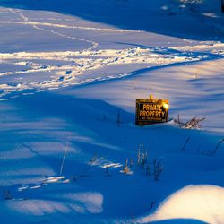 High angle view of information sign with text on snow covered landscape against sky