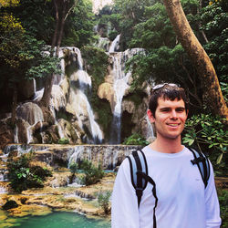 Portrait of young man against waterfall