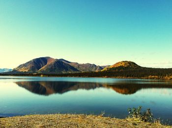 Scenic view of lake and mountains against clear blue sky