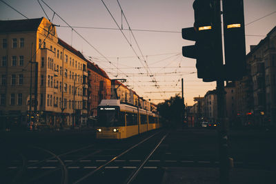 Train on city street against sky at sunset