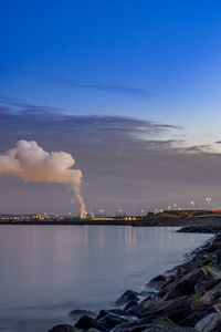 Smoke emitting from factory against blue sky