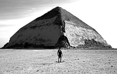 Rear view of man walking on field against sky