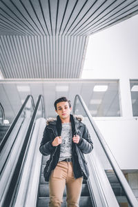 Portrait of young woman standing against railing