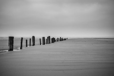 Wooden posts on beach against sky