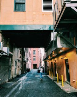 Rear view of woman walking on road amidst buildings in city