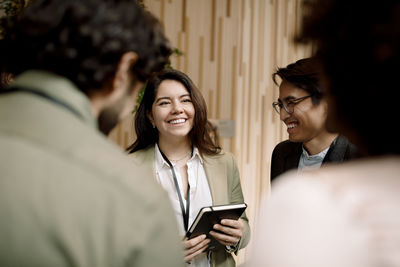 Smiling businesswoman discussing with male delegates in seminar at convention center