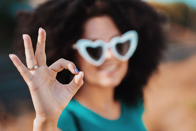 Portrait of smiling young woman showing ok sign