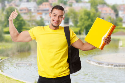 Portrait of young man standing against yellow water