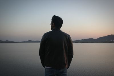 Rear view of man looking at sea against sky