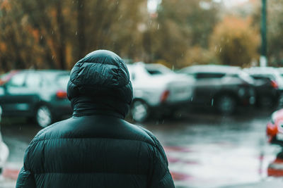 Rear view of person wearing raincoat in city during rainy season