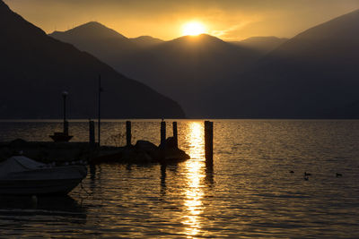 Silhouette man on boat in sea against sky during sunset