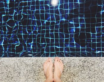 Low section of person standing by swimming pool