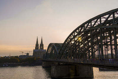 Bridge over river by buildings against sky