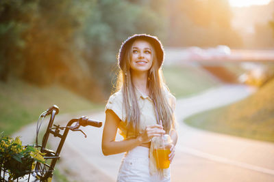 A happy girl in white shorts and a yellow blouse holds a glass of juice