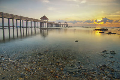 Pier over sea against sky during sunset